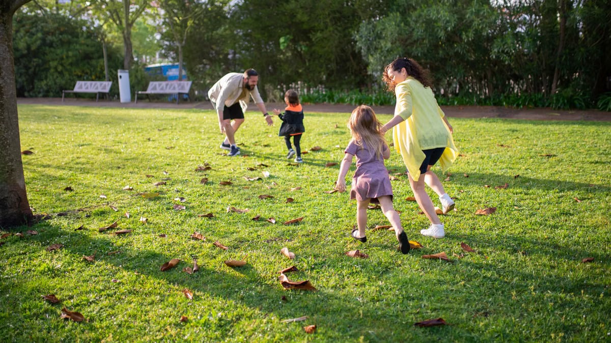 A joyful family playing together in a lush green park setting, enjoying a bright day.